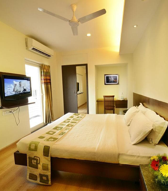 Spacious premium bedroom with modern interiors, cozy bedding, and comfort-focused design for guests